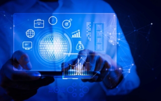 Threat Intelligence Automation. Hands holding a tablet device, with a glowing blue holographic interface showing icons for business, finance, and technology, all centered around a bright digital sphere.