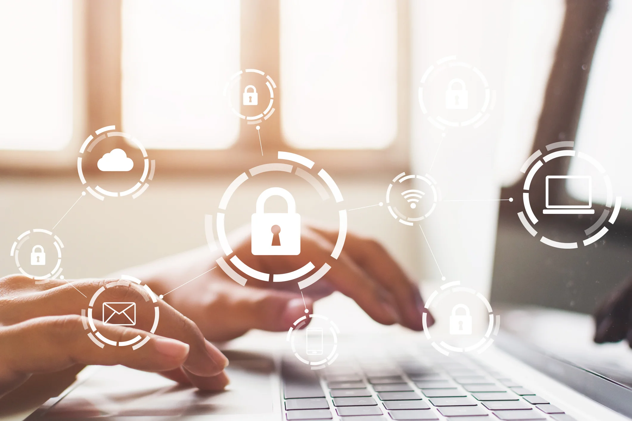 Legal compliance after ransomware. The image shows a close-up of someone typing on a laptop keyboard. Overlaid on the image are various icons representing cybersecurity, including a padlock, a cloud, an email symbol, and a laptop, all surrounded by circles, giving the impression of data protection or encryption.