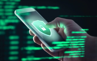 Ransomware remediation checklist. The image shows a hand holding a smartphone, and the phone's screen displays a large security shield icon with a padlock in the center, symbolizing protection or encryption. Overlaid on the image are streams of green digital code, reminiscent of the "Matrix" style, giving the impression of a cybersecurity context. The green code fills the background, suggesting data or a security system. The focus is on securing mobile devices, emphasizing encryption or protection from hacking or data breaches.