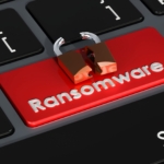 Ransomware impact assessment. The image shows a close-up of a computer keyboard with a red key labeled "Ransomware." The word "Ransomware" is printed in white, contrasting sharply with the red background of the key, which signifies urgency or a threat. Positioned on top of the "Ransomware" key is a small icon of a broken padlock, symbolizing a security breach or vulnerability. This visual metaphor suggests the concept of ransomware as a pressing cybersecurity threat, warning users about the potential risk associated with it.