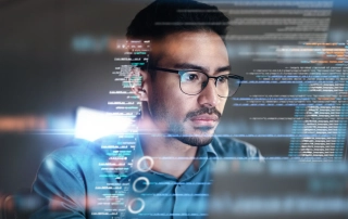 The image shows a man wearing glasses, intensely focused on a computer screen. He appears to be a programmer or someone working with code, as lines of code and data seem to float in front of him as a digital overlay. The man has short, dark hair, facial hair, and a thoughtful expression as he examines the information. The scene is futuristic, with a soft glow reflecting off the code, evoking a sense of technology and problem-solving, possibly in a cybersecurity or programming environment.