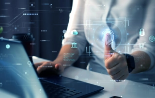 Documenting your ransomware response. The image features a person sitting at a desk, using a laptop. The individual is giving a thumbs-up gesture, and their thumb is highlighted with a glowing digital fingerprint, symbolizing biometric security or authentication. Floating around the thumb and computer are various icons and graphics, including padlocks, network symbols, and digital connections, representing different elements of cybersecurity, data protection, and secure access. The background is filled with a futuristic digital interface, emphasizing the concept of advanced technology and identity verification.