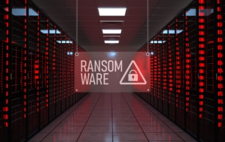 Recovering from Netwalker ransomware attack. This image depicts a data center with rows of server racks illuminated by red lights, creating an intense and alarming atmosphere. Hanging in the center of the image is a translucent sign displaying the word "RANSOMWARE" in bold white letters, accompanied by a warning triangle icon with a padlock inside it. The perspective draws attention to the central aisle, which is well-lit and contrasts with the red glow of the servers, emphasizing the theme of cybersecurity threats and the urgency of ransomware attacks. The overall mood is stark and ominous, fitting for the subject of digital vulnerabilities.