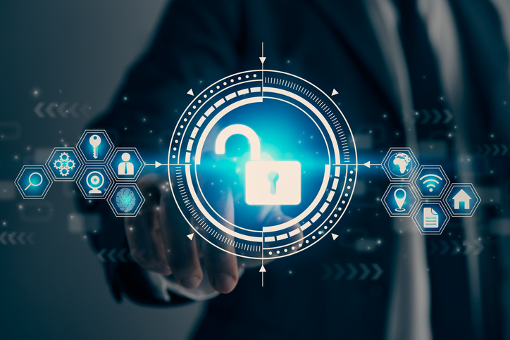 Automated backup solutions for ransomware. The first image shows a glowing blue circle in the center with a white open padlock symbol, representing digital security or access. Around the circle, a futuristic interface includes dotted circular patterns and glowing icons connected by lines, forming a hexagonal network. These icons depict security-related concepts, such as a key, a magnifying glass, and a fingerprint. The background is dark and blurred, with a person's hand extending towards the circle, as if interacting with the digital interface.