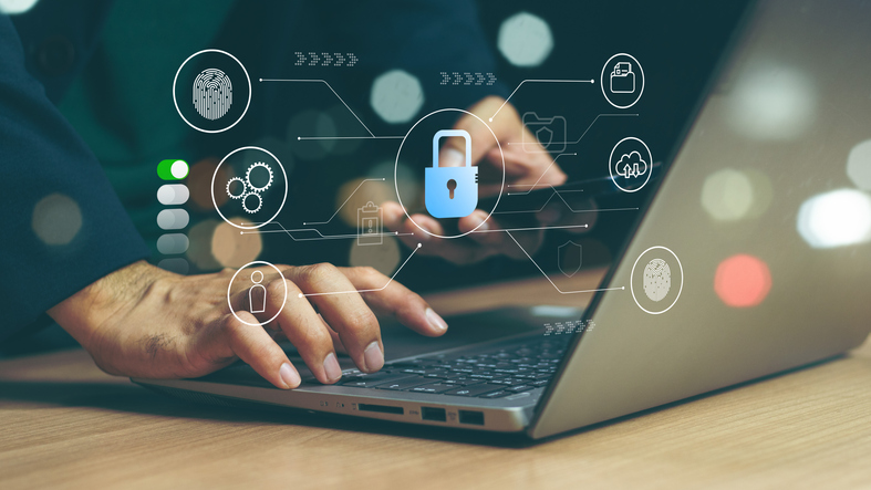 Post-attack cybersecurity roadmap. A person is typing on a laptop in a dimly lit environment, with a glowing digital security interface overlaying the screen. The icons displayed include a padlock, a user profile, and gears, representing cybersecurity, access control, and system optimization.