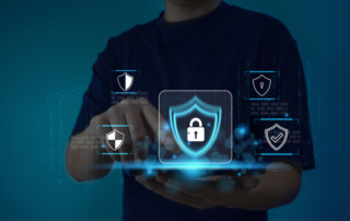 Third-party risk management for ransomware. A person sitting at a desk using a laptop. Their hand points towards a glowing shield icon with a padlock at its center. A web of connected icons surrounds the shield, representing cybersecurity, digital networks, and data protection.