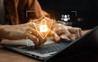 Cybersecurity war room strategies. A person is typing on a laptop keyboard, wearing an earth-toned sweater. A golden, glowing security shield icon with a padlock is digitally overlaid on the hands. Additional icons appear, including a user login interface, symbolizing online security or access control. The background is dark and slightly blurred, with soft lighting highlighting the hands and laptop. Small floating, glowing security icons add a tech-heavy cybersecurity theme.