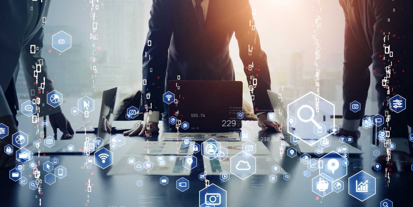 Encrypted Backup Services. Several people in business attire stand around a conference table with laptops open. The scene is overlaid with floating digital icons — like magnifying glasses, graphs, Wi-Fi symbols, cloud storage, and security shields — suggesting a high-level meeting about technology, cybersecurity, or digital strategy. Warm light filters through the background.