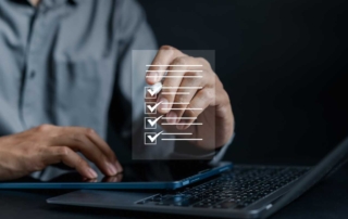 Secure Email Filtering for Businesses. A person in a gray button-down shirt uses a touchscreen device. Floating above their hand is a transparent checklist graphic with several items marked. The image suggests digital task management, compliance checking, or project organization.