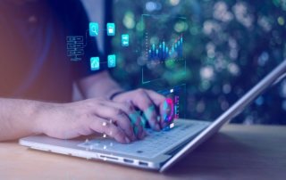 Ransomware tabletop exercise planning. This image shows a close-up of a person typing on a white laptop outdoors. The scene is visually enhanced with digital overlays — glowing, transparent icons and data charts that appear to float above the laptop. These graphics include bar charts, pie charts, folder structures, and magnifying glasses, suggesting data analysis, cybersecurity, or tech operations. The person’s hands are the main focus, and the background is softly blurred greenery, giving a natural, calm setting that contrasts with the high-tech visual effects layered on top. The image conveys a theme of working on advanced technology or cybersecurity in a remote or casual environment.