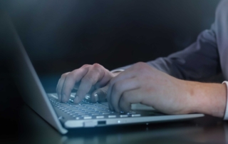 Intellectual property ransomware protection. A man in a suit types on a laptop, set against a dark background with no holograms.