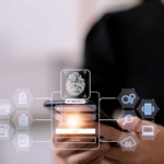 sd-wan-security-optimization SD-WAN Security Optimization. A person holding a smartphone, with a transparent holographic interface showing a fingerprint icon, padlock, and other security-related symbols hovering in front of the device.