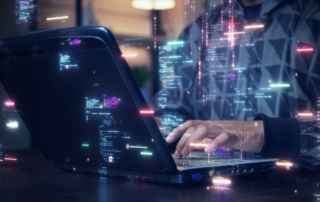 Cyber Threat Modeling Techniques. A person typing on a laptop in a dimly lit room. Bright, multicolored lines of code and data streams appear as glowing overlays, giving a sense of high-tech programming or cyber activity.